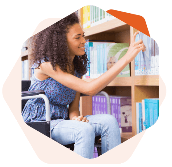 Mulher negra cadeirante sorrindo enquanto escolhe algum livro na prateleira