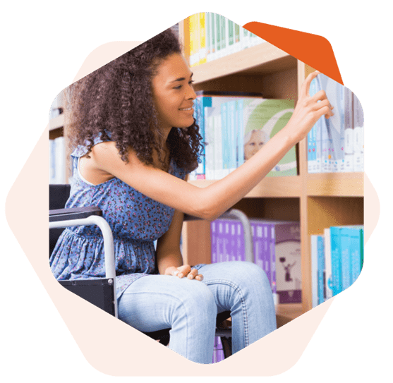 Mulher negra cadeirante sorrindo enquanto escolhe algum livro na prateleira