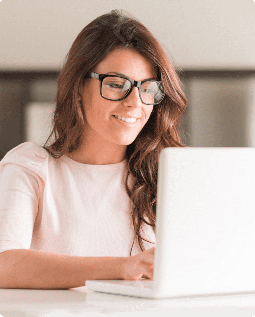 Mulher de óculos sorrindo enquanto utiliza o notebook